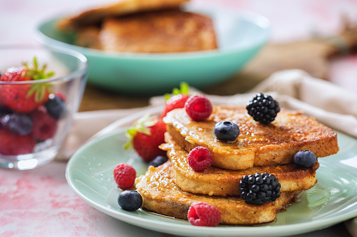 Preparing french toast flavored with fresh berry fruits and drizzled with maple syrup